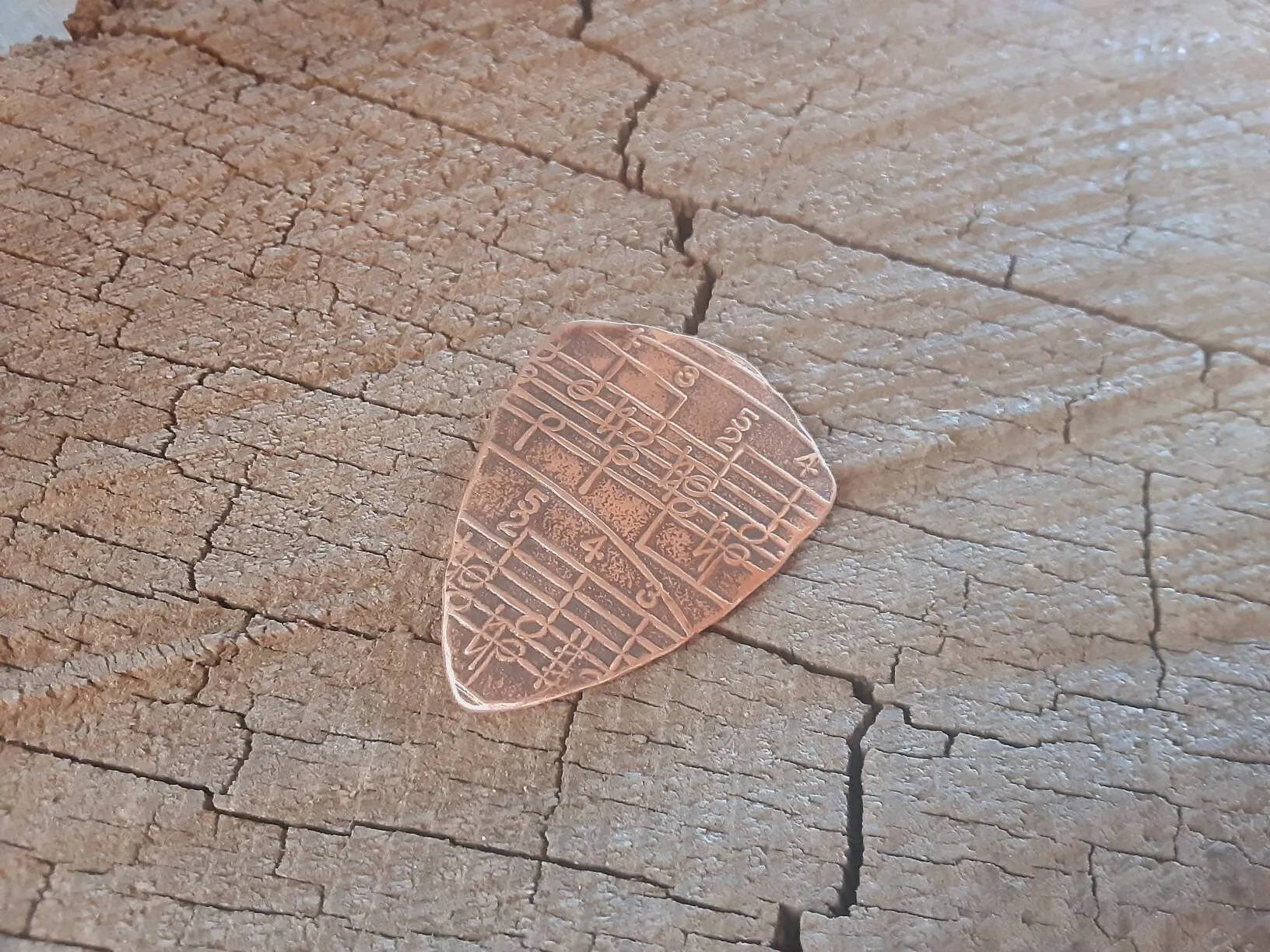 Copper shield shape guitar pick with music notes