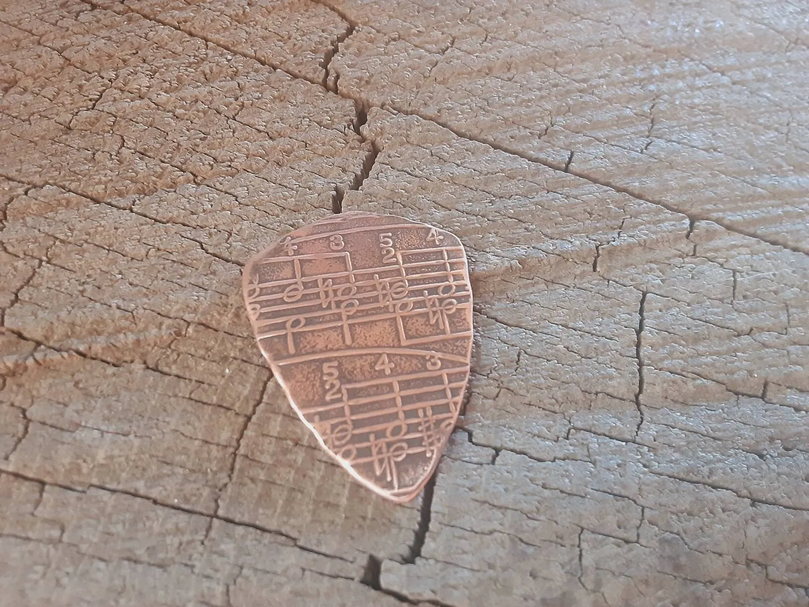Copper shield shape guitar pick with music notes