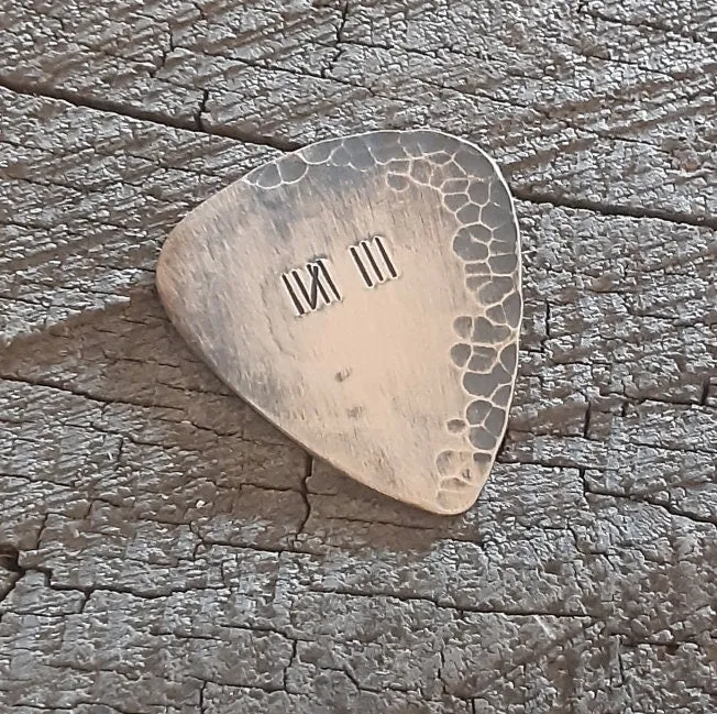 Distressed and rustic bronze guitar pick with tally mark