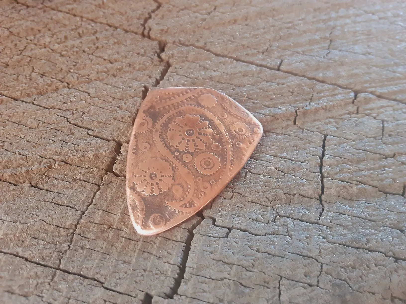 Guitar pick with paisley pattern in copper