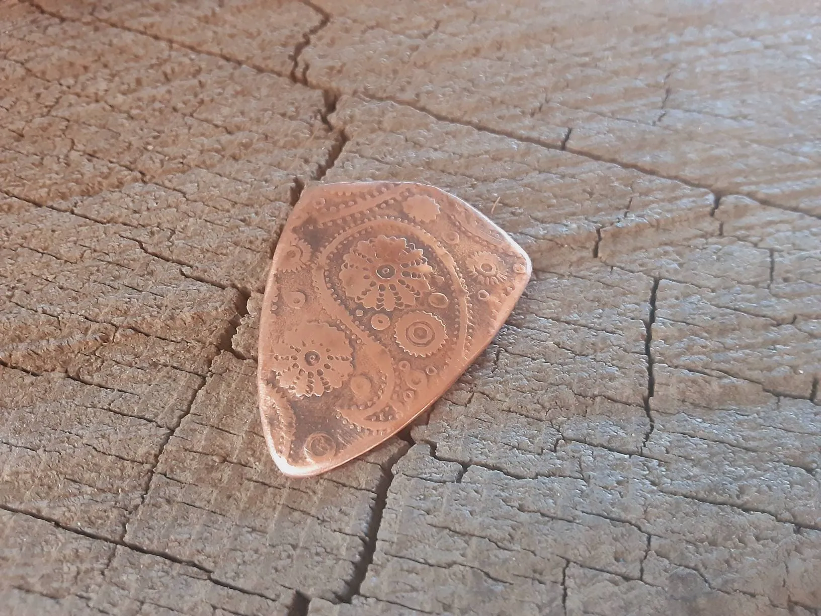 Guitar pick with paisley pattern in copper