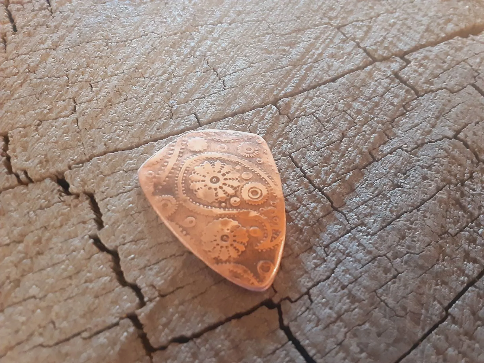 Guitar pick with paisley pattern in copper