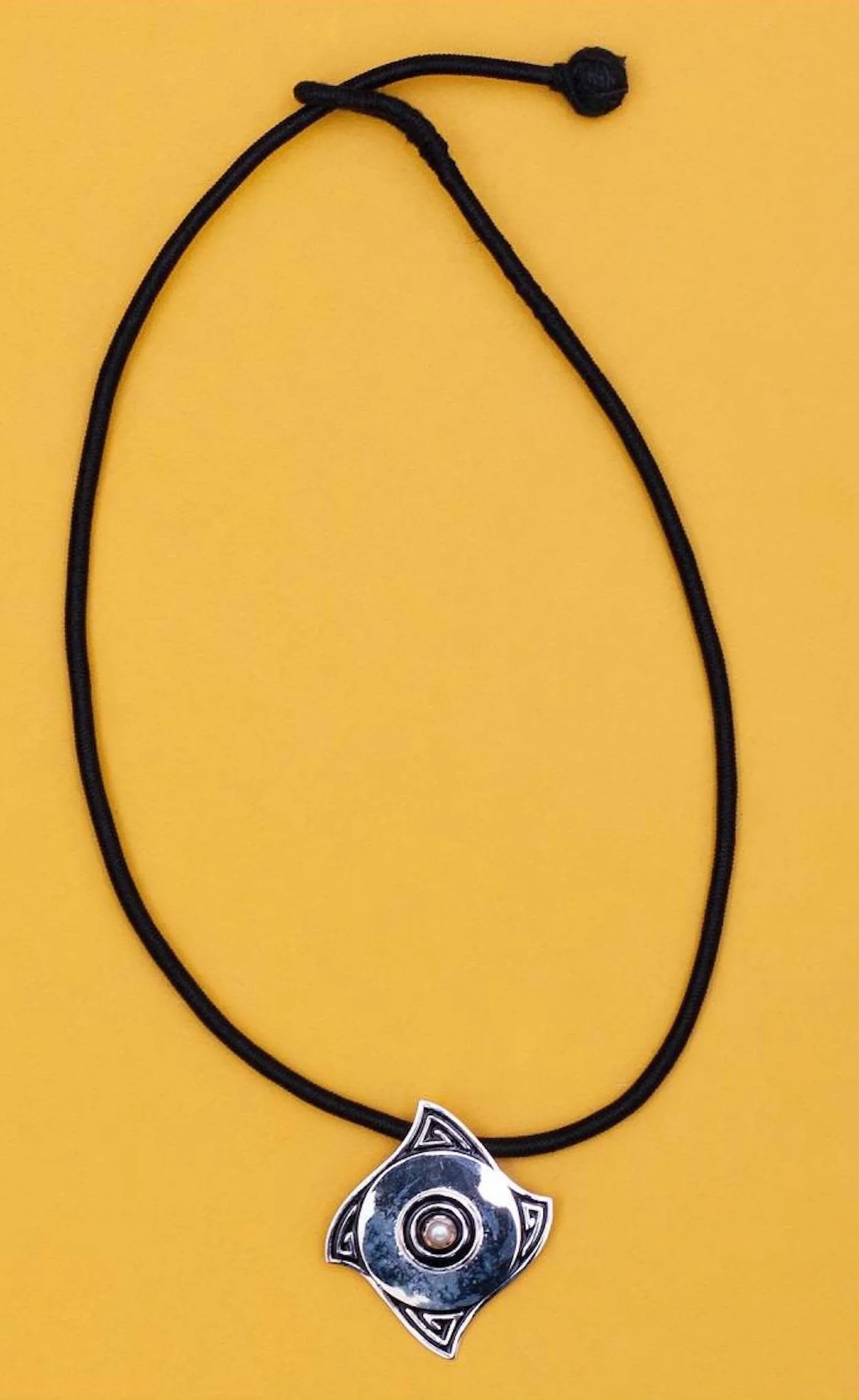 Minimalist, curved diamond shape pendant with a pearl center and fine black enamel work