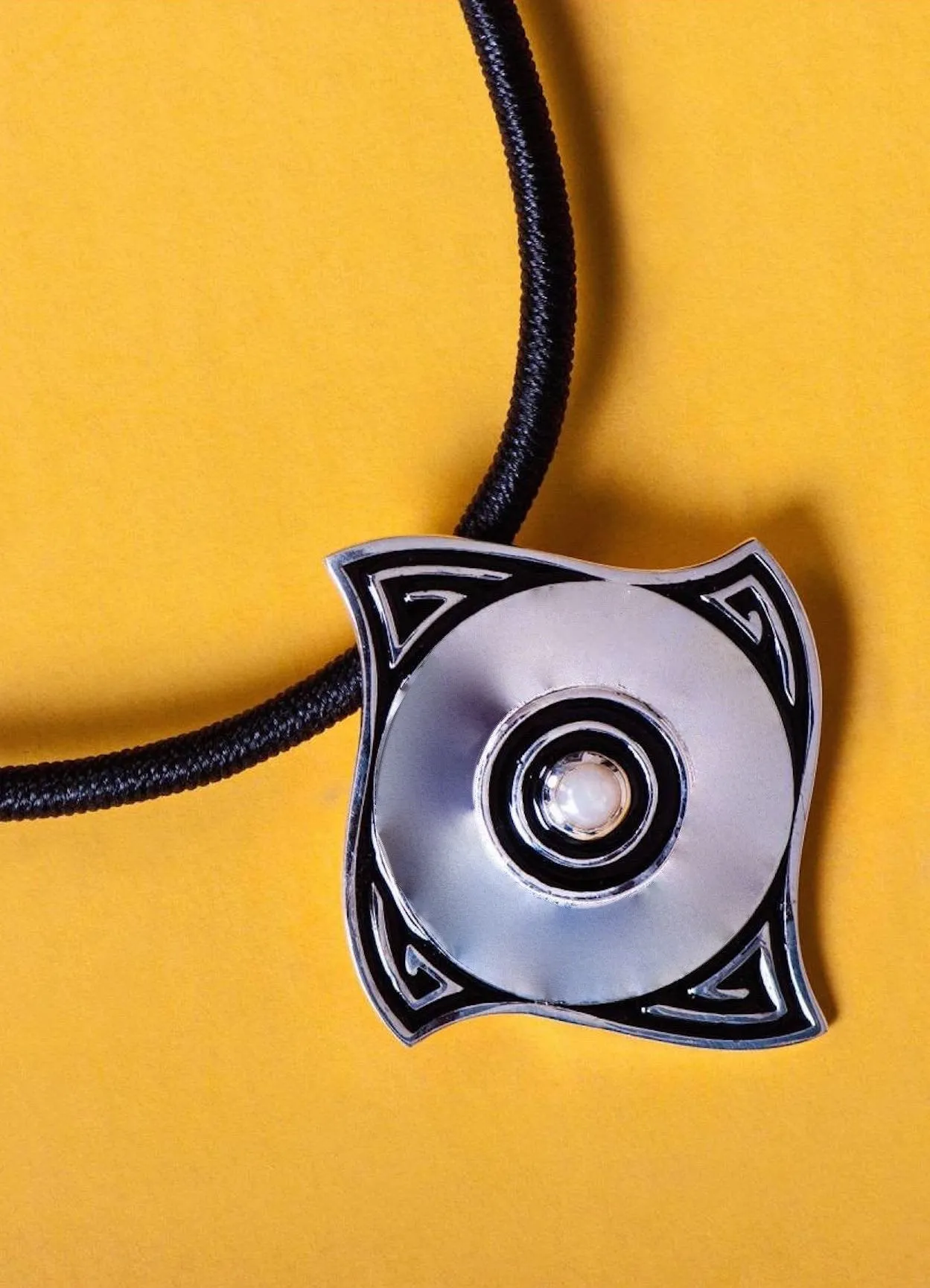 Minimalist, curved diamond shape pendant with a pearl center and fine black enamel work