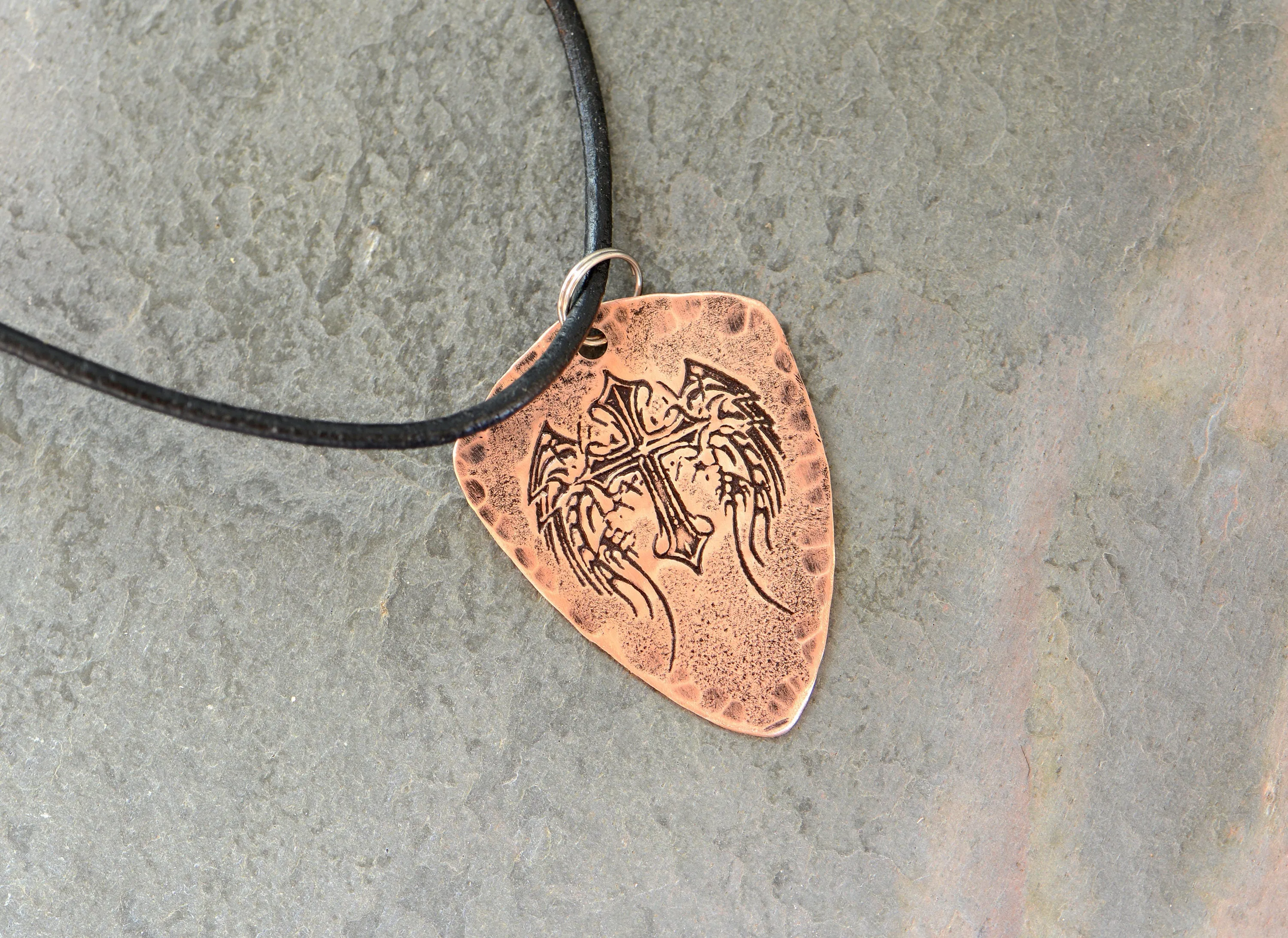 Shield style copper guitar pick necklace featuring a winged cross